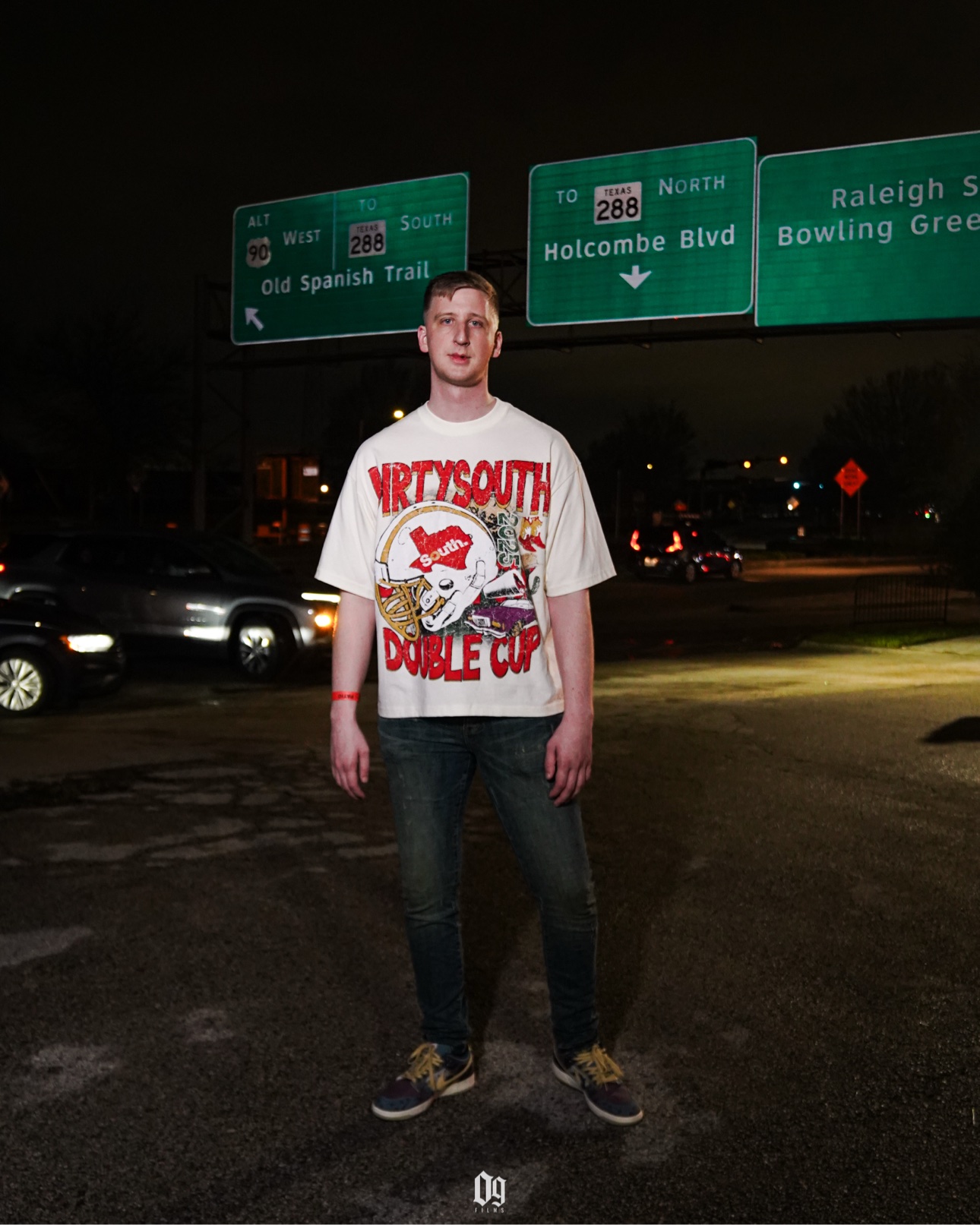 C-Hold standing under Houston highway signs at night